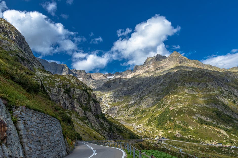 A breathtaking view of a winding road through the Swiss Alps under a clear summer sky.