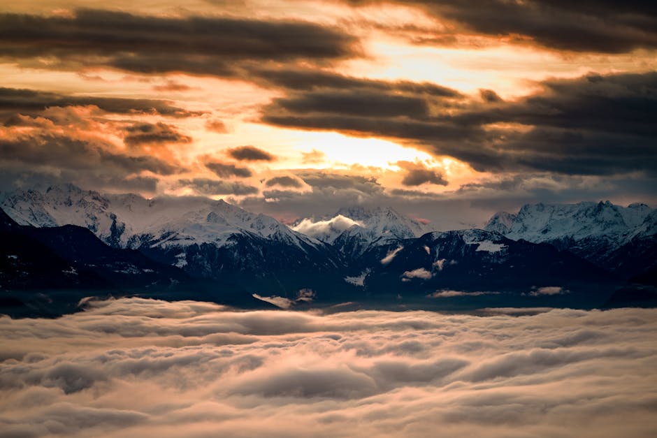 A breathtaking view of snow-capped mountains at sunrise over a sea of clouds in Crans-Montana, Switzerland.